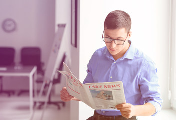 Handsome businessman reading newspaper in office