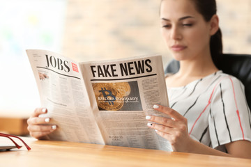Young businesswoman reading newspaper in office