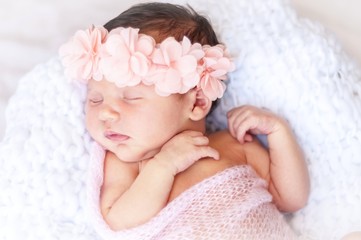 Cute sleeping newborn Caucasian baby girl a pink flower head bow. Sweet infant girl in her sleep. A...