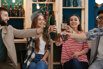 Group of cheerful friends drinking beer in bar