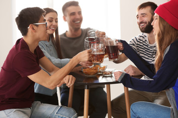 Group of friends clinking glasses with beer in bar