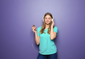 Fototapeta na wymiar Beautiful young woman listening to music on color background