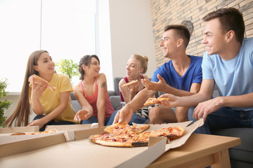 Young people having fun at party with delicious pizza indoors