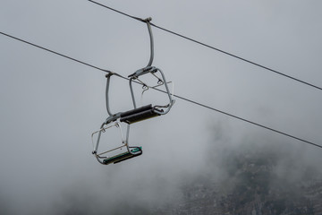 Naklejka premium A chairlift with mountains and fog in the background