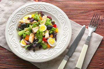 Plate with tasty chicken salad on wooden table