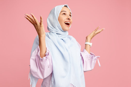 Happy Surprised Arab Woman In Hijab. Portrait Of Smiling Girl, Posing At Pink Studio Background. Young Emotional Woman. The Human Emotions, Facial Expression Concept. Front View.