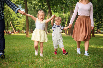 Naklejka na ściany i meble Happy family walking in green park