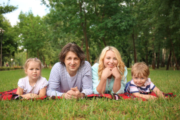Fototapeta premium Happy family resting on plaid in park