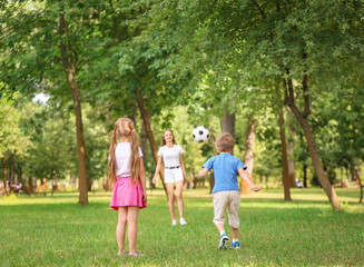 Fototapeta premium Happy family playing football in park on summer day