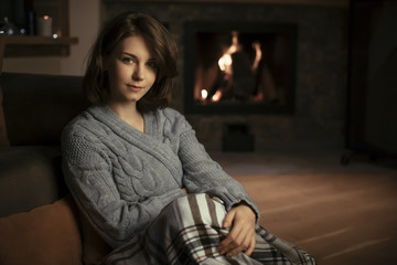 Fototapeta premium Pretty Woman Sitting by the Fireplace