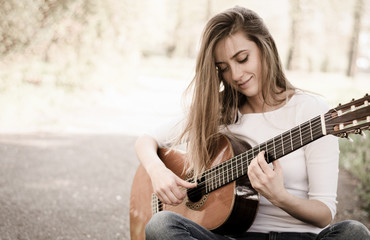 Beautiful young girl playing guitar in park. Vintage.