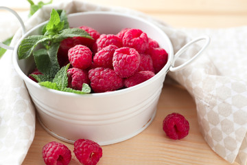 Bowl with delicious raspberries on table