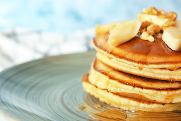 Tasty pancakes with sliced banana and walnuts on plate, closeup