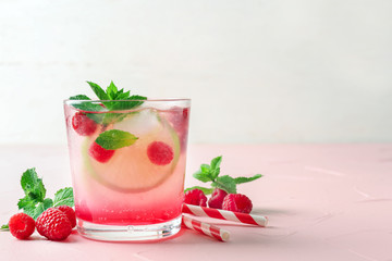 Glass of fresh raspberry mojito on table