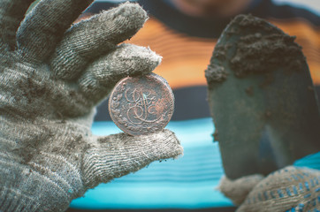 Aged 5 kopeks coin of Russian empire in the hand of coin finder. Treasure hunting concept. In...