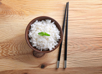 Bowl with boiled white rice on wooden table