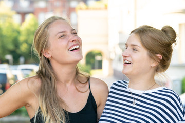 Two cheerful female friends listening to a phone