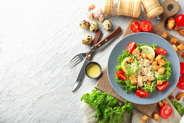 Plate with tasty Caesar salad on table