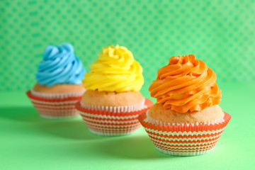 Delicious birthday cupcakes on color background