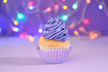 Delicious birthday cupcake against blurred lights