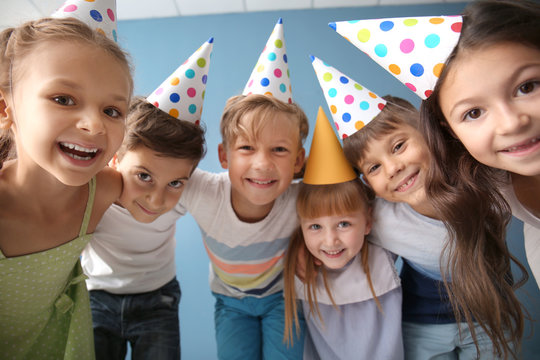 Cute little children in Birthday hats against color background