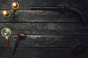 Musket gun, magnifying glass, smoking pipe, wallet and burning candle on wooden table background.