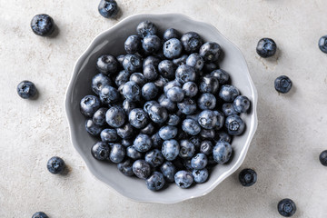 Bowl with ripe blueberries on light table