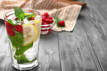 Glass of fresh raspberry mojito on wooden table