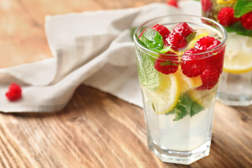 Glass of fresh raspberry mojito on wooden table