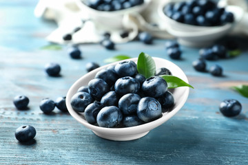 Bowl with ripe blueberries on wooden table