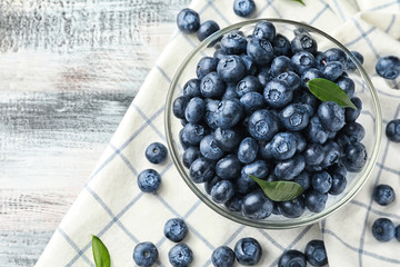 Bowl with ripe blueberries on wooden table