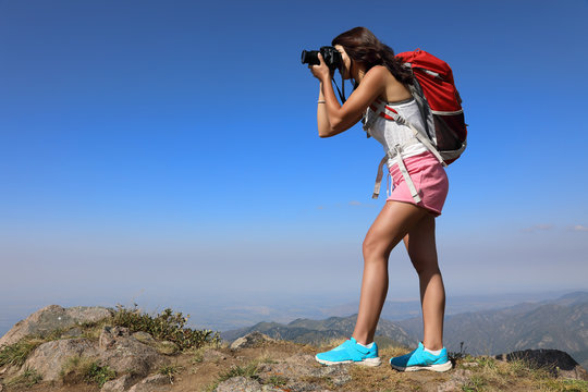 Young woman traveler taking photo on mountain peak