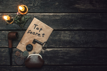 Top secret documents file, key, smoking pipe and wallet with coins on the detective spy agent table...