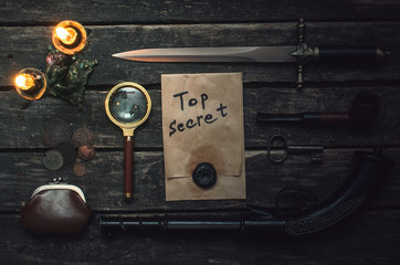 Top secret documents file, musket gun, dagger, magnifying glass, smoking pipe, and wallet with coins on the detective spy agent.