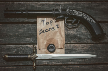 Top secret documents file, musket gun and dagger knife on the wooden table.