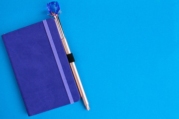 Purple notebook with pen on a blue background