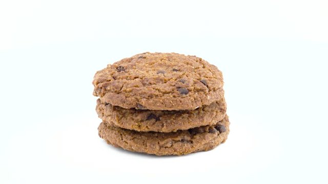Full frame of a three soft and chewy chocolate chip oatmeal cookies rotating on the turntable. Isolated on the white color background. Close-up. Macro.