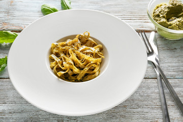 Plate of delicious pasta with pesto sauce on wooden table