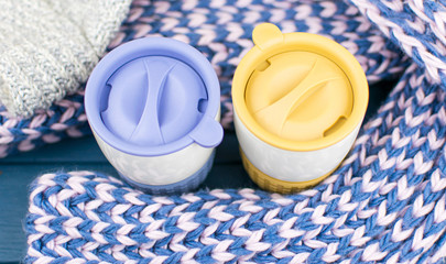 Two terry mugs of different colors are wrapped in a warm scarf.