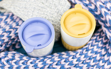 Two terry mugs of different colors are wrapped in a warm scarf.