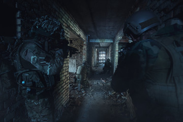 Fototapeta na wymiar Special Forces soldiers in action. Elite squad sneak up to the enemy in a dilapidated building.They use special equipment, weapons and tactical devices