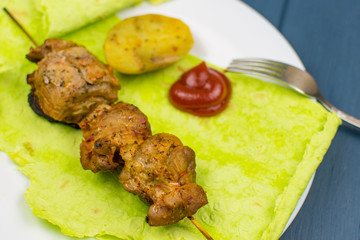 Fried meat on green pita bread with spinach and peas and baked potatoes.