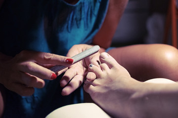 Female pedicure. Care for feet and toenails. Master conducts procedures for foot care.