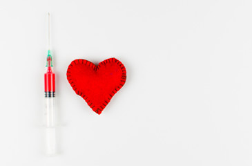 Heart and syringe  with red liquid on white background.