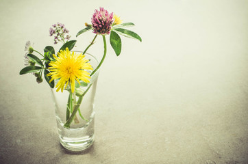 A small bouquet of wildflowers in a glass. Vintage toned image.