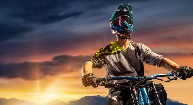 Mountain biker on sunset trail. Male cyclist portrait in sport helmet