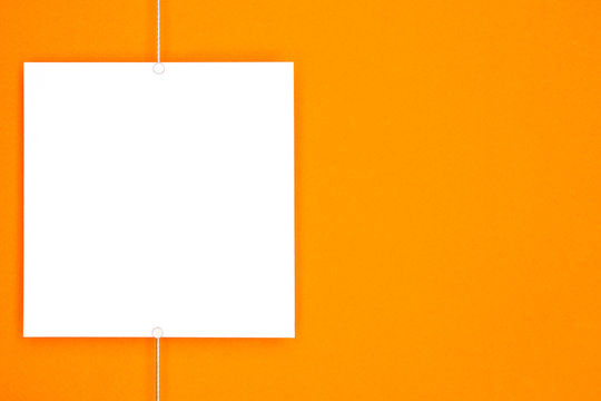 Paper card (photo frame) hanging on metal rope with magnets on orange background