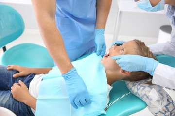 Dentist examining little boy's teeth in clinic