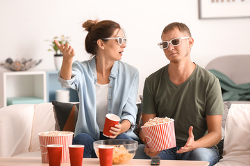 Couple eating popcorn while watching TV at home