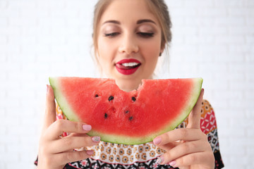 Beautiful young woman with slice of tasty watermelon on light background